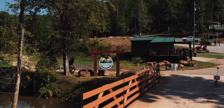 The wooden bridge over the creek with the resort sign and buildings beyond