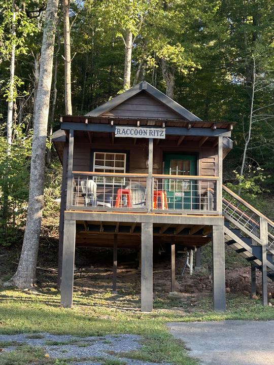 The Raccoon Ritz, a cabin on stilts with a railed porch and side stairs